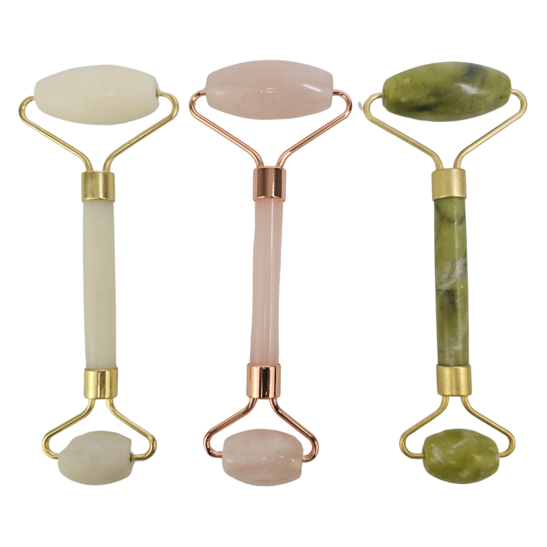 Three crystal face rollers in white, pink and green stone, standing side by side in metal frames