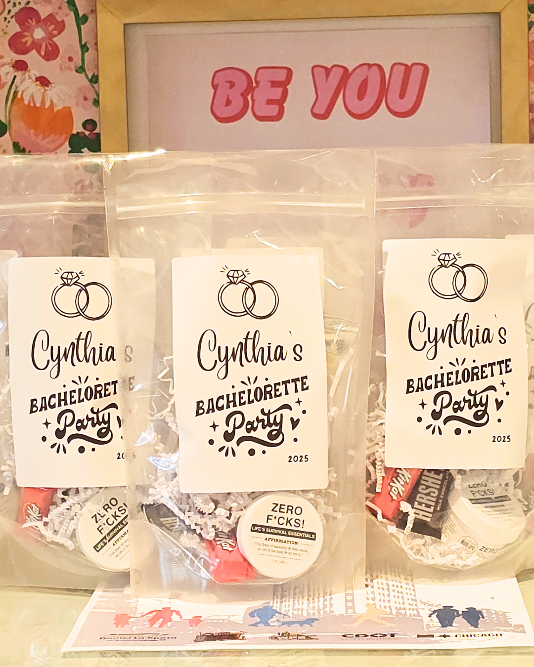 Custom party favor bags for a bachelorette party, in front of a Be You sign