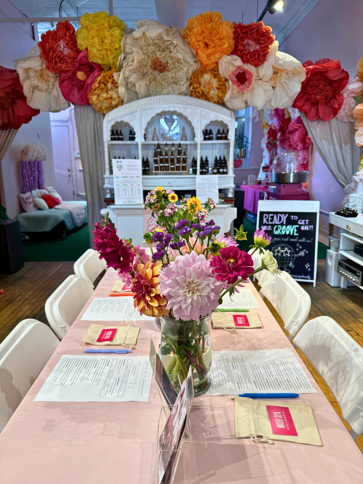 A long table set for a workshop, with a vase of flowers and a worksheet at each seat
