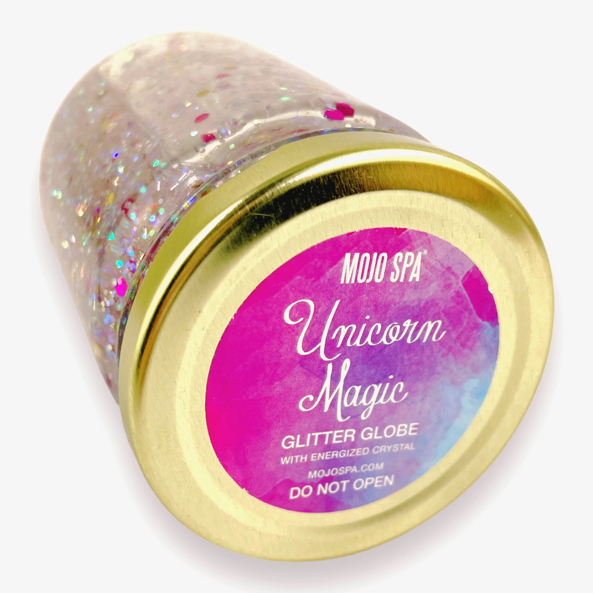 The jar tilted to show its gold lid, with a Mojo Spa logo and a label reading Unicorn Magic Glitter Globe