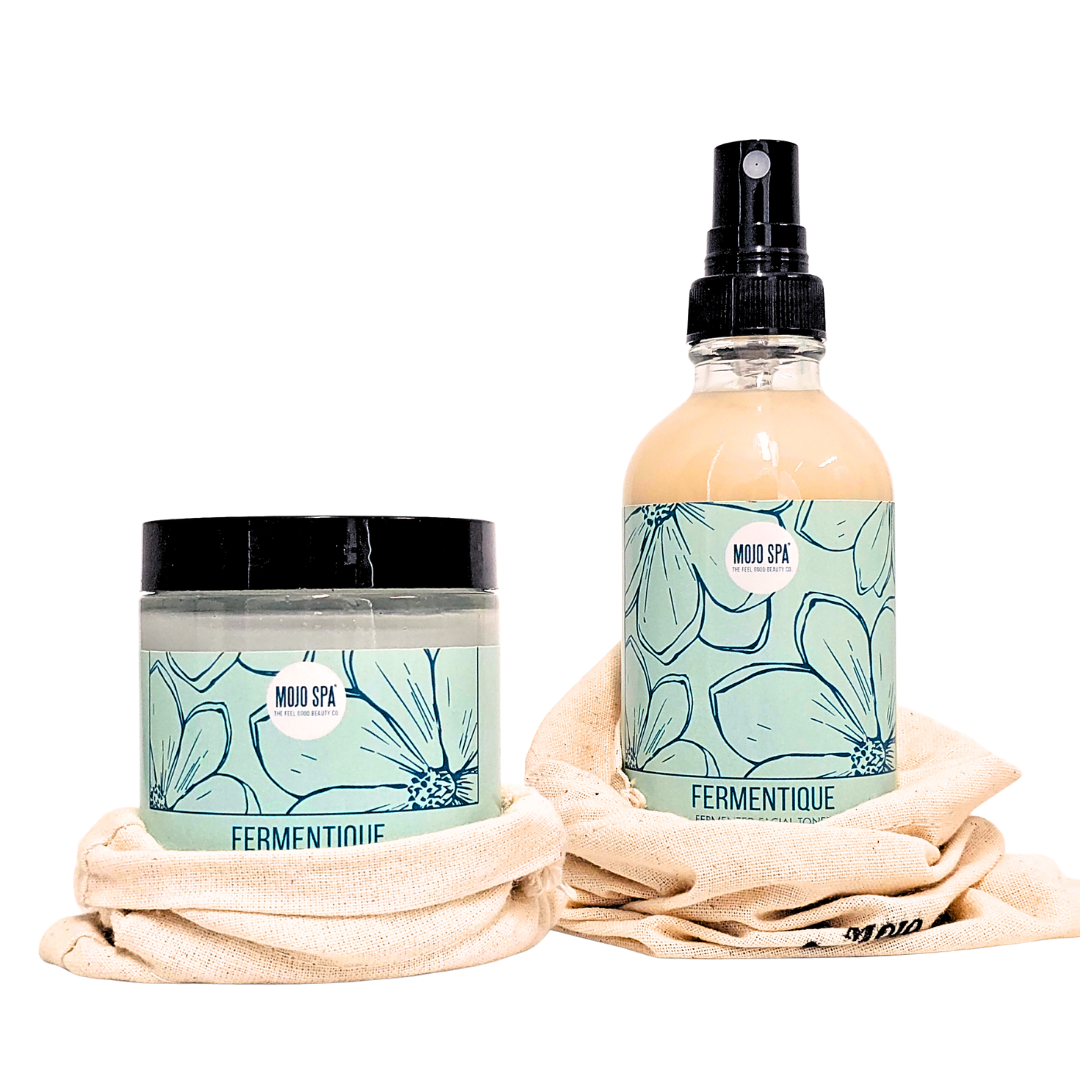 A jar and a spray bottle, each with a teal flower label, resting on cream cotton bags