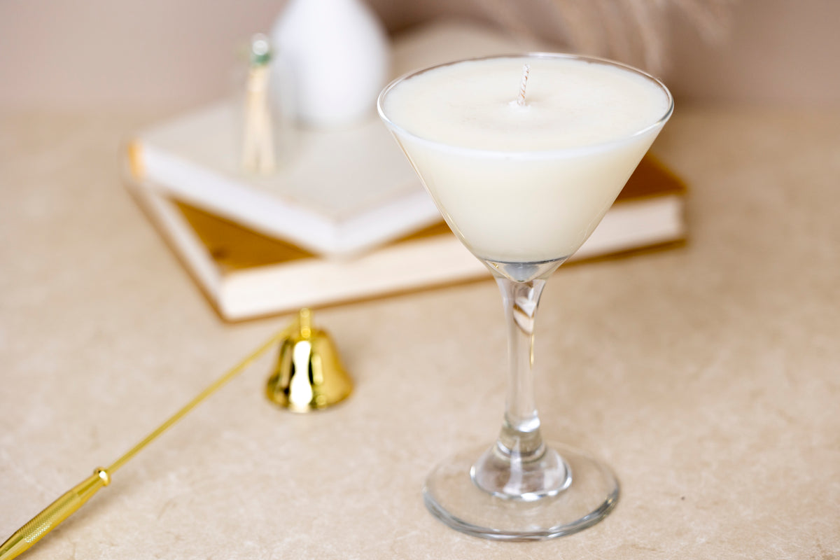 The unlit candle in its martini glass beside stacked books, a jar of matches and a gold snuffer