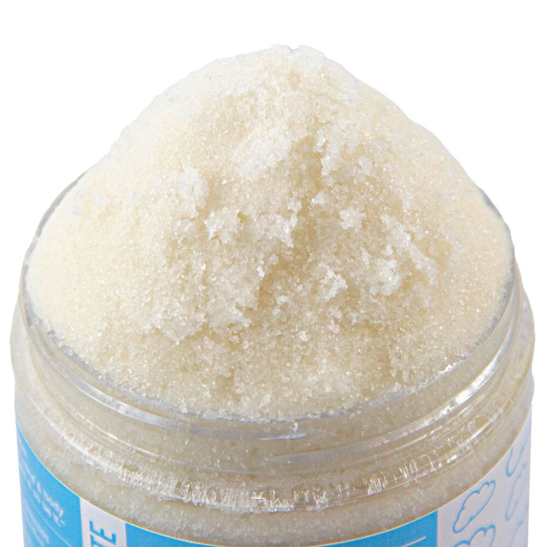 A close-up of the cream and white scrub crystals at the top of the open jar