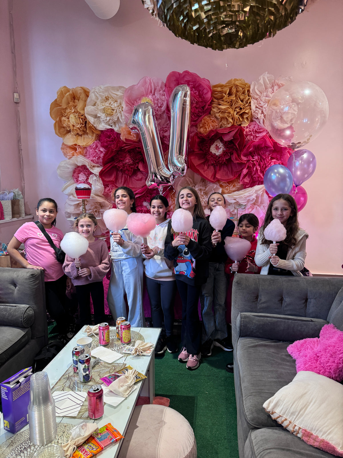 Party guests holding cotton candy under number 11 balloons