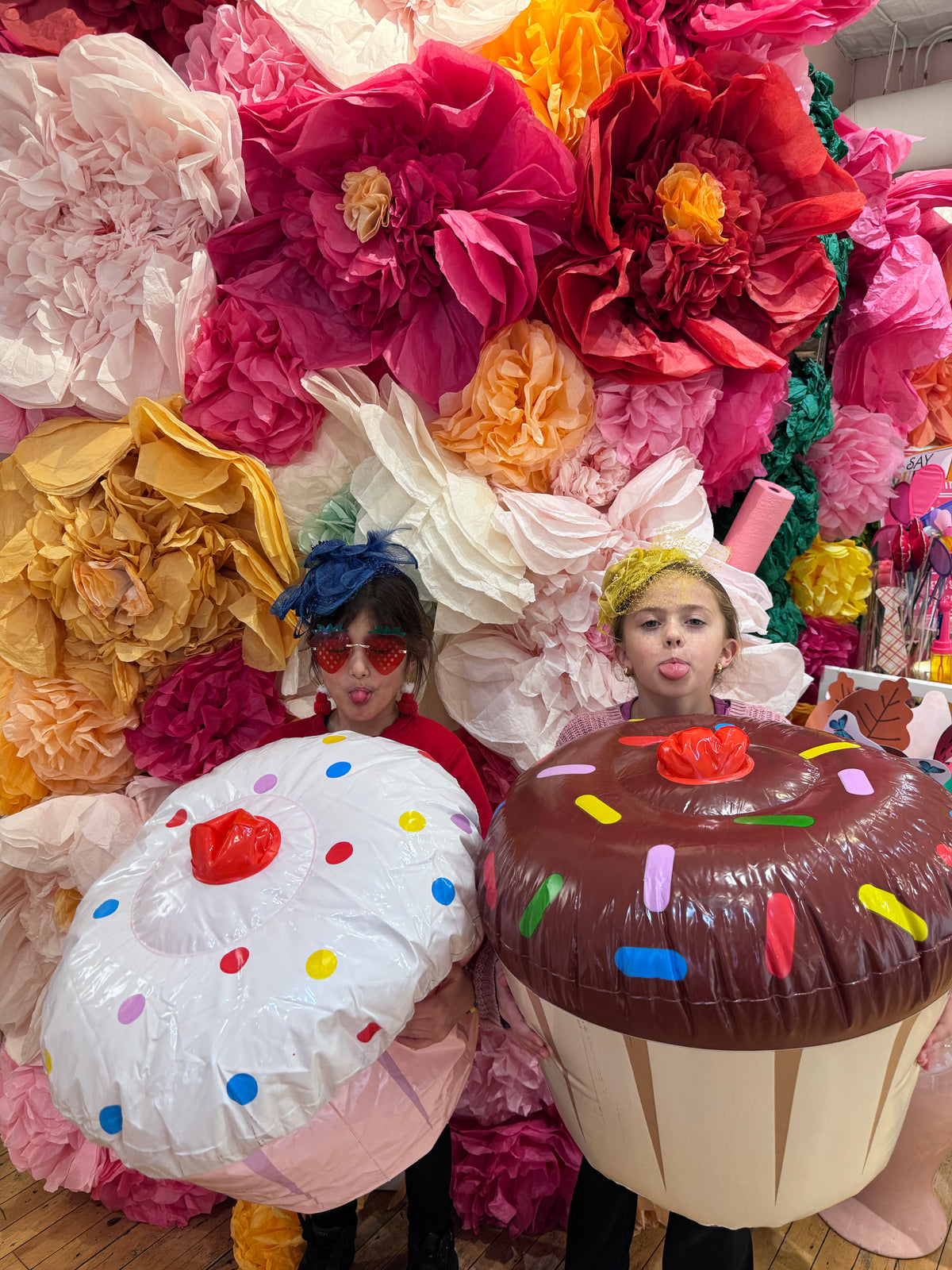 Two party guests in inflatable cupcake costumes, one sticking out her tongue