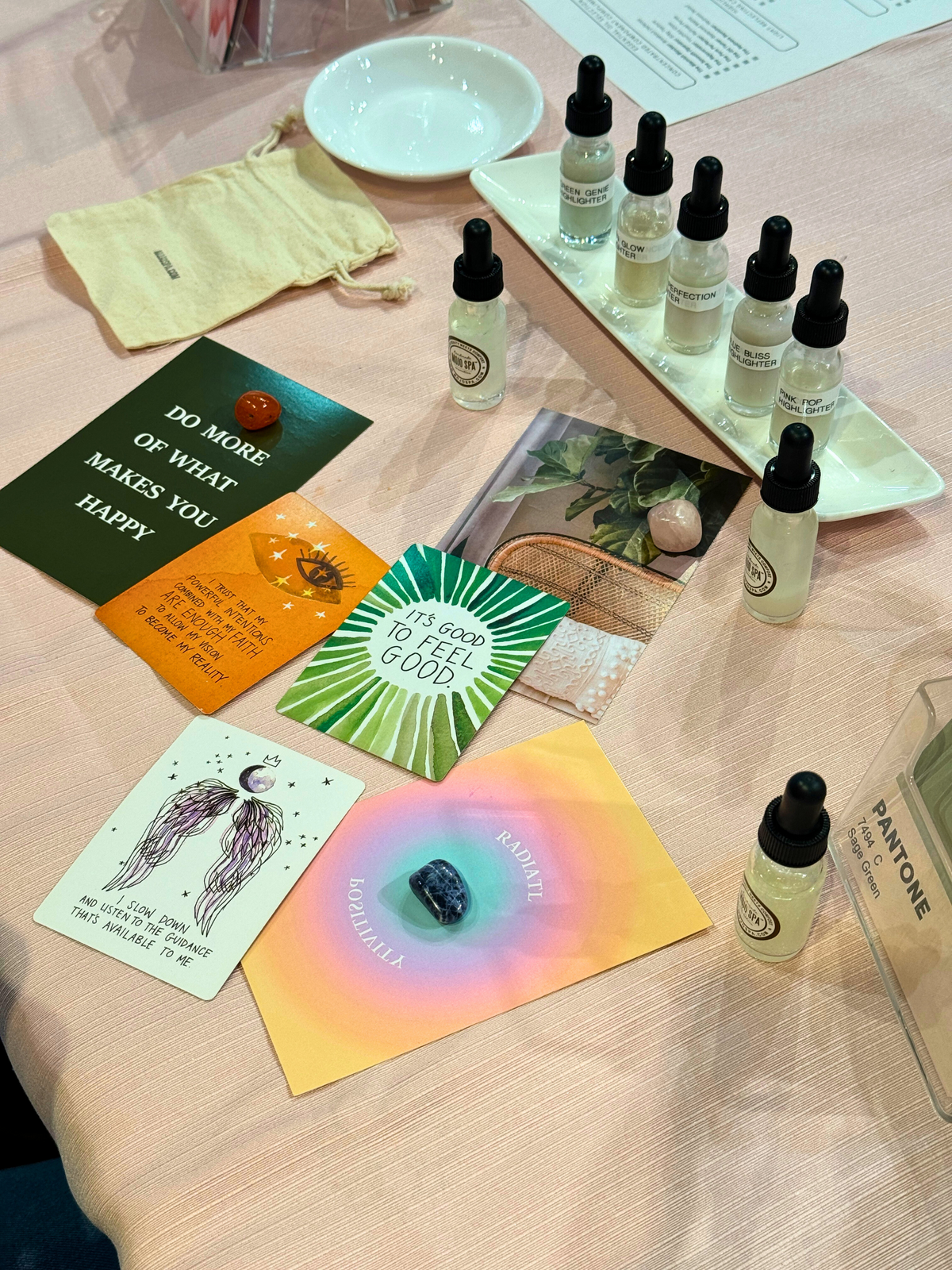 Affirmation cards, a crystal and dropper bottles laid out on the Beauty Bar table