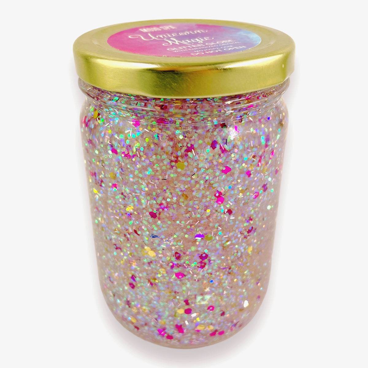 The jar upright, filled with multicolour glitter under a gold lid with a pink and purple label