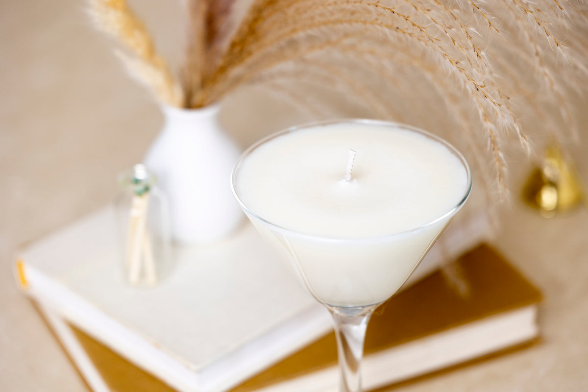 A close view of the white wax from above, with a vase of pampas grass, books and a jar of matches behind