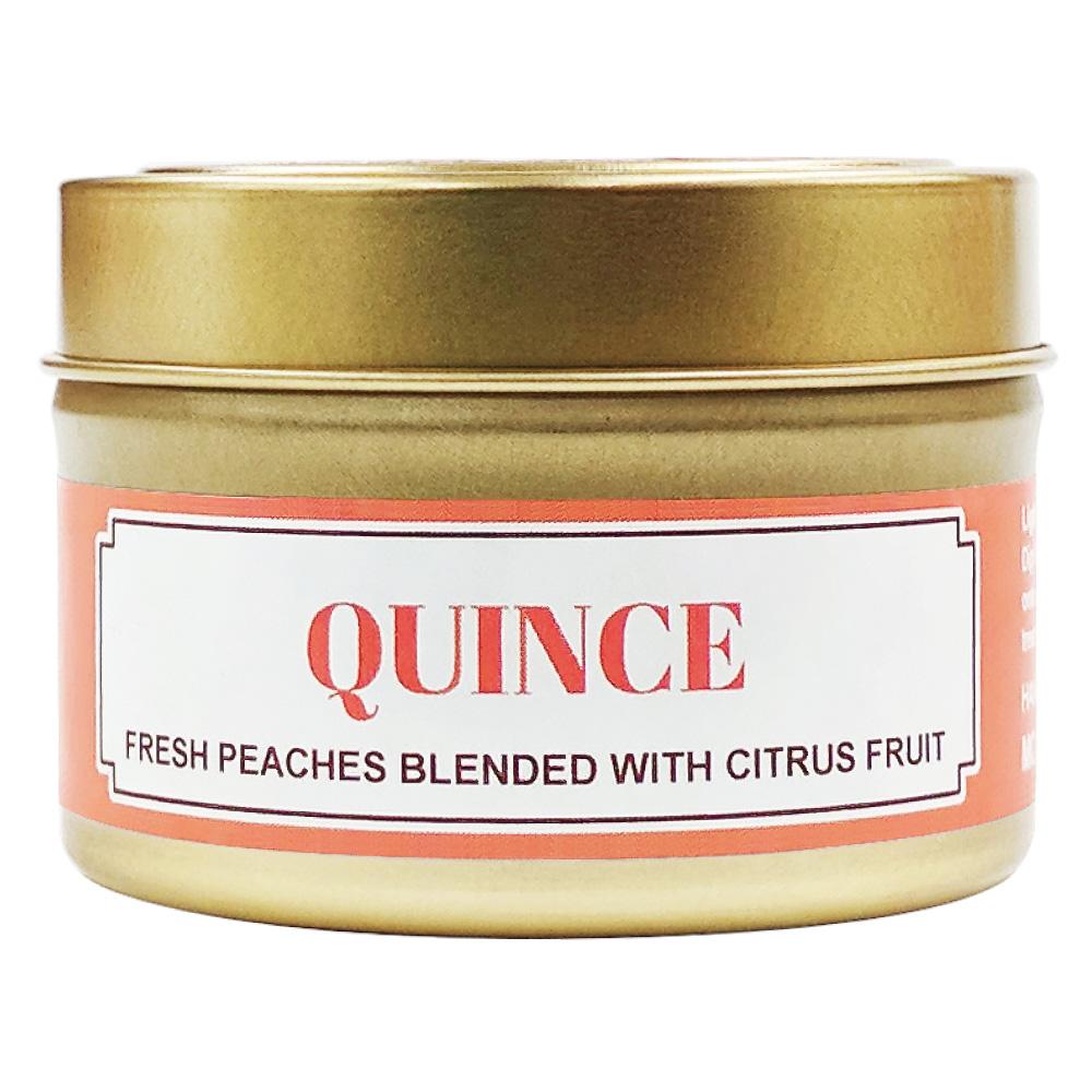 Quince soy massage candle in a gold tin with a coral label reading fresh peaches blended with citrus fruit