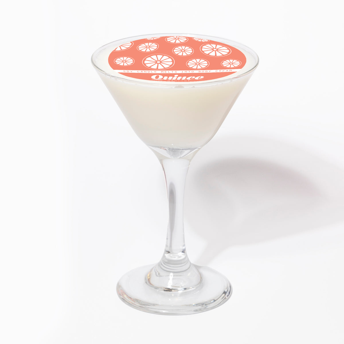 The candle from the side, showing the white wax in the glass beneath the coral Quince label